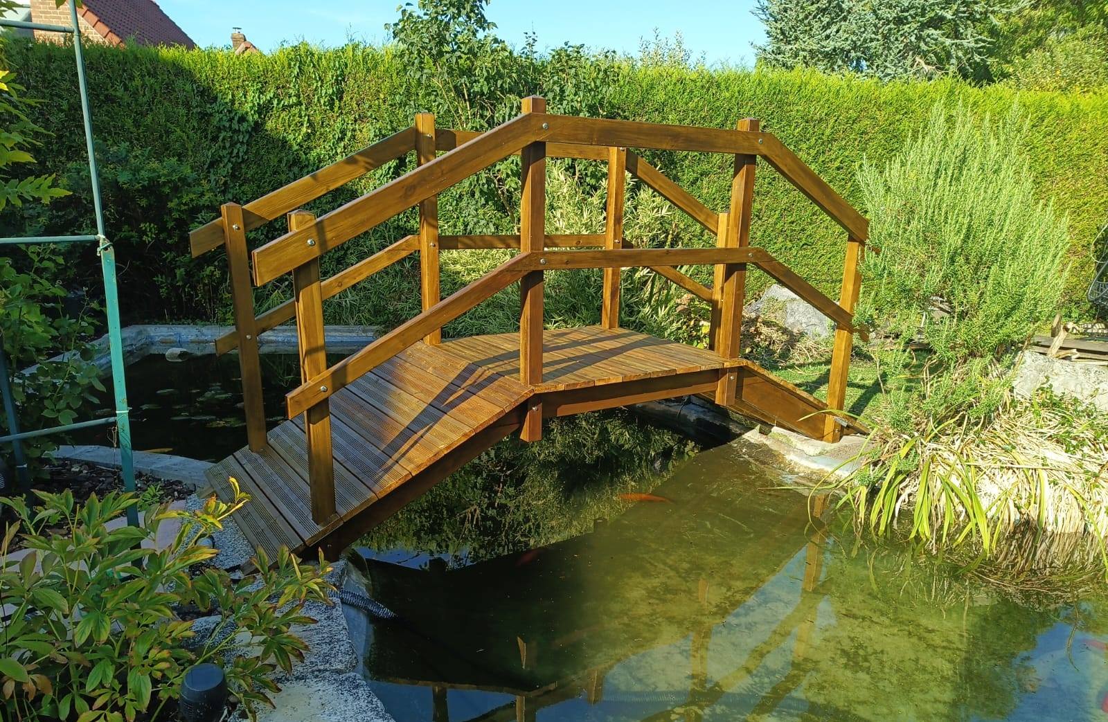 Pont de jardin en bois massif courbé avec rambardes au-dessus d'un bassin